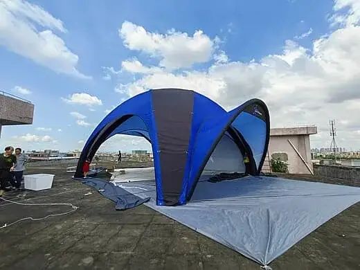 Tente araignée gonflable bleue installée sur l'herbe pour un événement en plein air