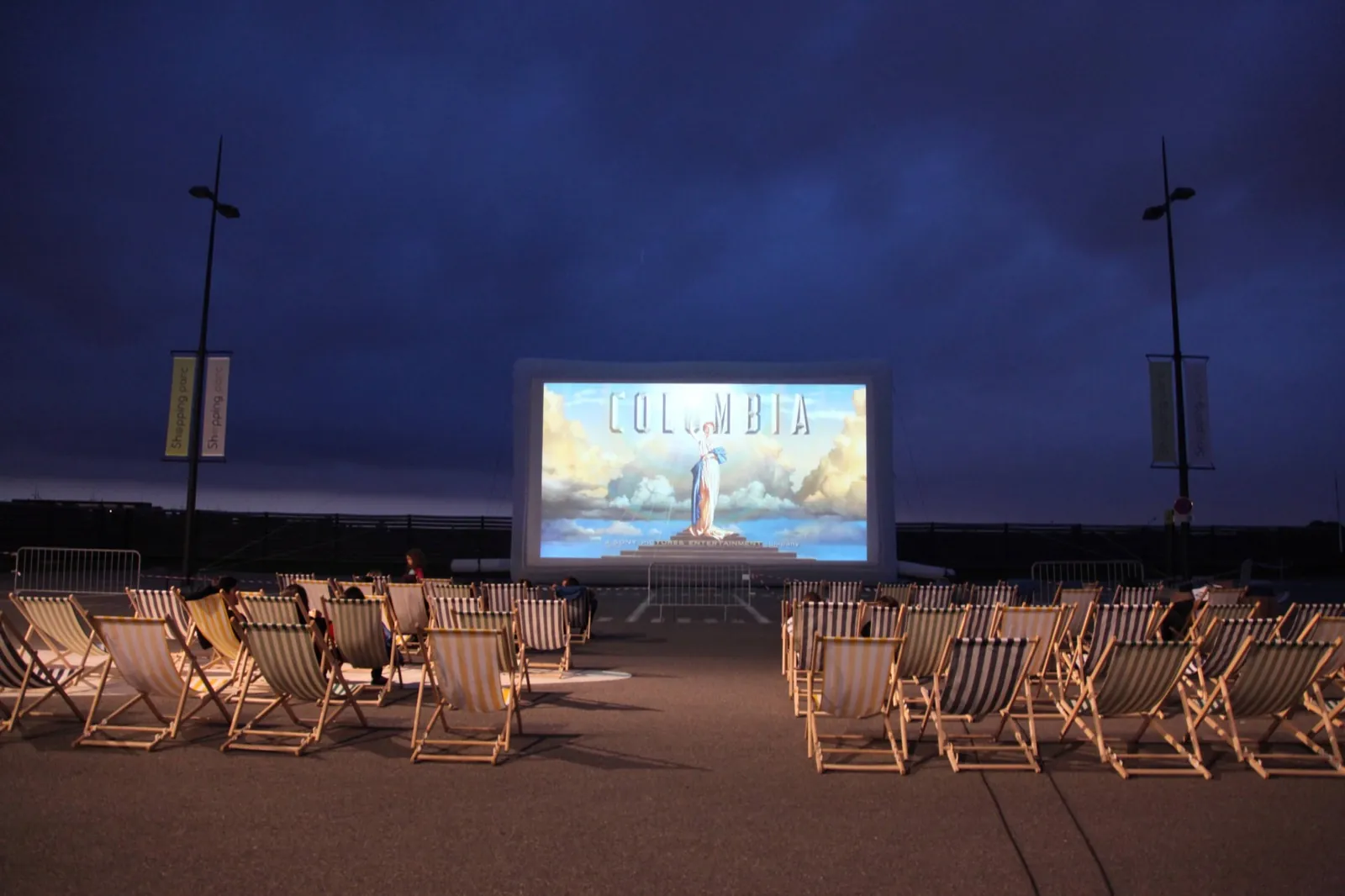 Écran de cinéma gonflable géant Hallucine installé en plein air, transats face à l'écran à la tombée du jour
