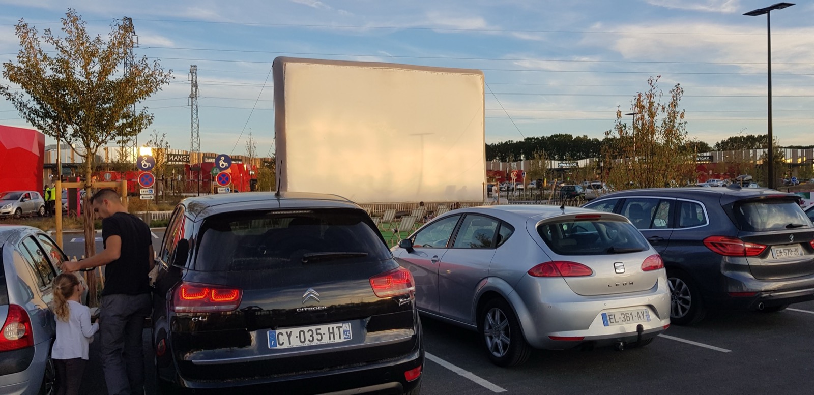Schermo cinematografico gonfiabile “Hallucine” allestito per una proiezione in drive-in, con le auto di fronte allo schermo