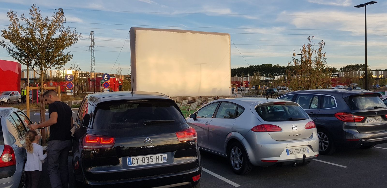 Aufblasbare Kinoleinwand „Hallucine“, aufgestellt für eine Drive-in-Vorstellung, Autos vor der Leinwand